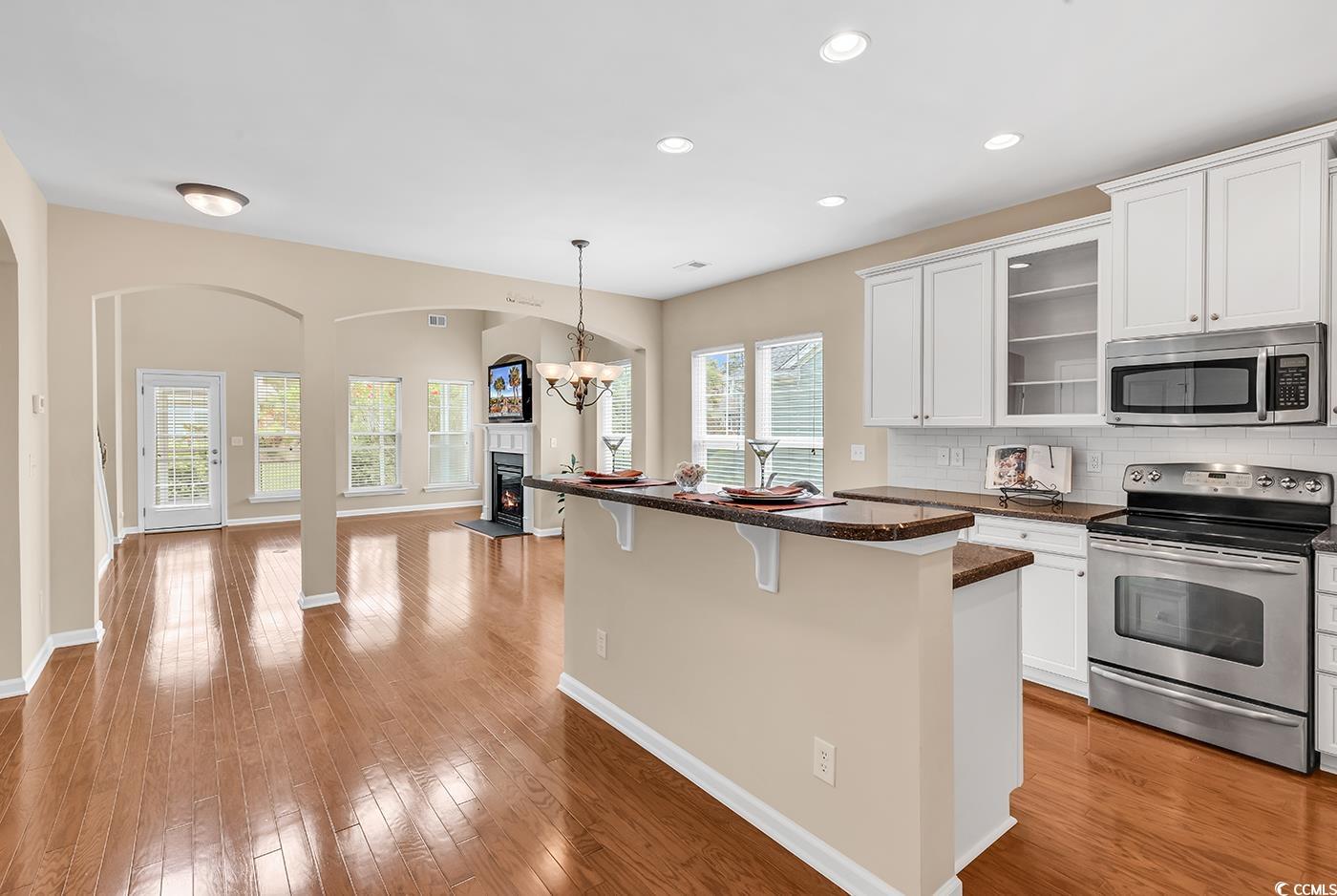 126 Dreamland Drive Murrells Inlet, SC 29576 - Photo 40 of 40 Kitchen featuring stainless steel appliances, a kitchen breakfast bar, open floor plan, arched walkways, and glass insert cabinets