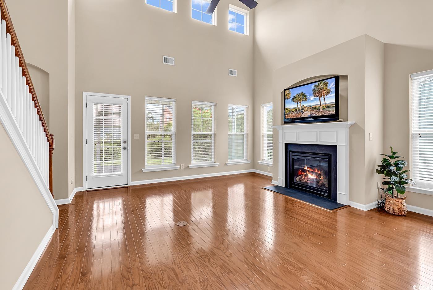 126 Dreamland Drive Murrells Inlet, SC 29576 - Photo 9 of 40 Unfurnished living room with a ceiling fan, a glass covered fireplace, stairs, wood finished floors, and baseboards