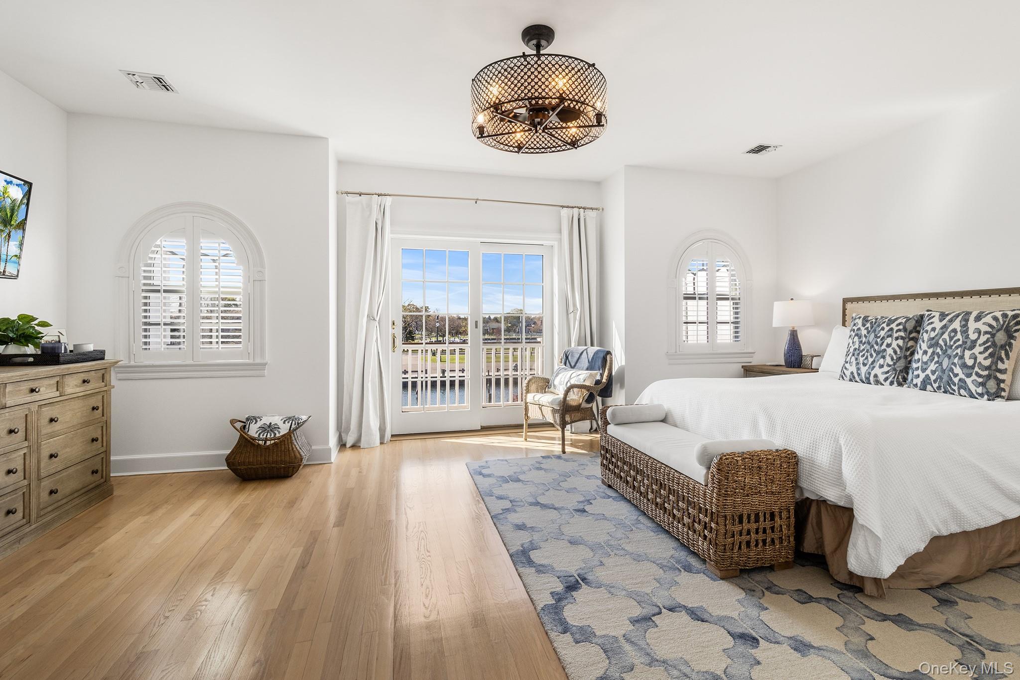 7 Salt Meadow Road, Unit 7 Babylon, NY 11702 - Photo 19 of 35 a bedroom with a large bed and a chandelier