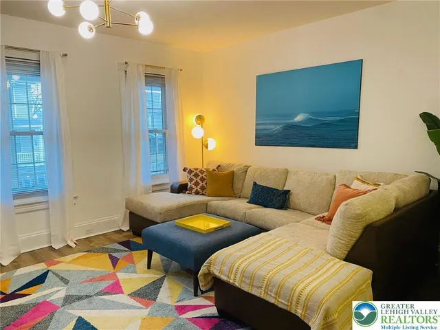 a living room with two bed and a lamp with wooden floor