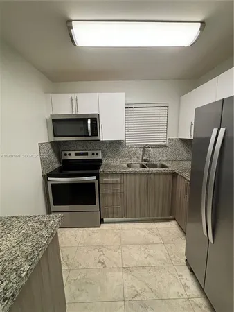 a kitchen with granite countertop a refrigerator and a stove top oven