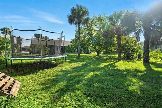 an aerial view of a residential houses with outdoor space and trees all around