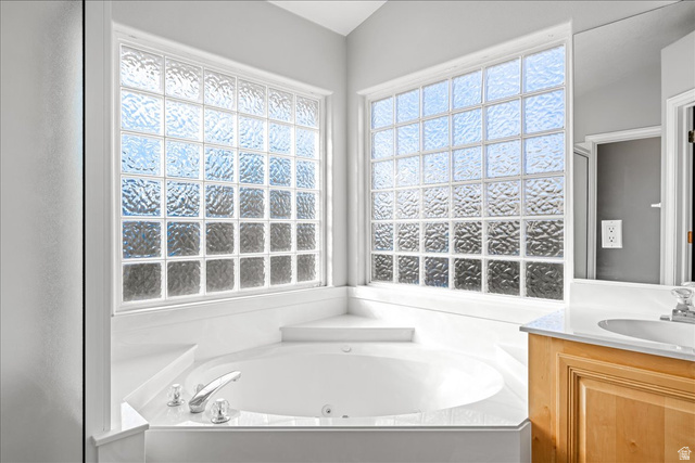 7 Reflection Way St. George, UT 84770 - Photo 44 of 54 Bathroom featuring a jetted tub, vanity, and plenty of natural light