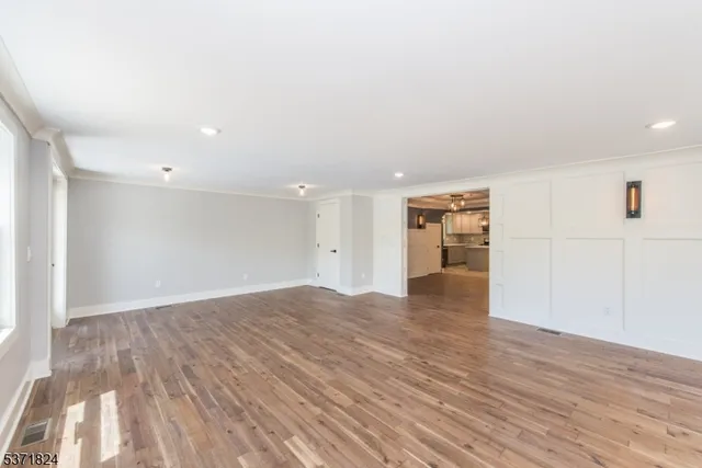 a view of an empty room with wooden floor and closet