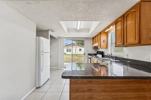a kitchen with kitchen island granite countertop a stove a sink and a refrigerator with wooden floor