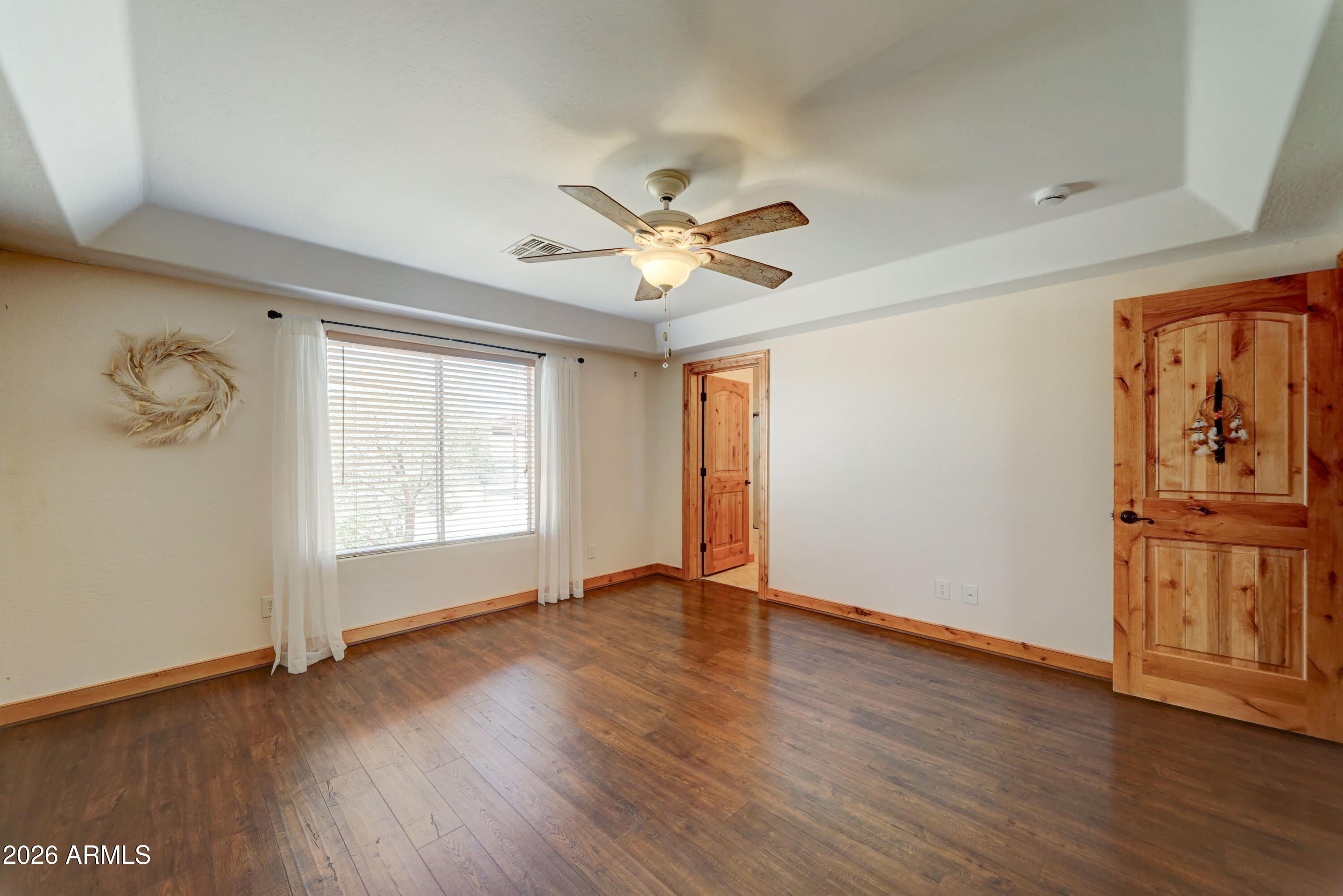 4642 North Tomahawk Road Apache Junction, AZ 85119 - Photo 13 of 41 an empty room with wooden floor chandelier fan and windows