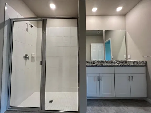 a bathroom with a granite countertop sink a mirror and a shower