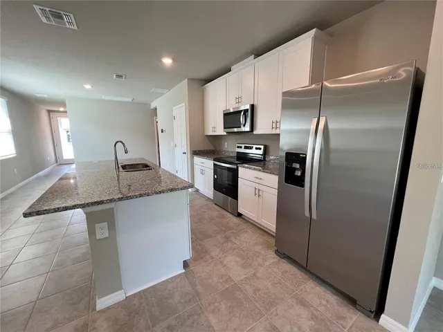 a kitchen with stainless steel appliances granite countertop a refrigerator a stove and a sink