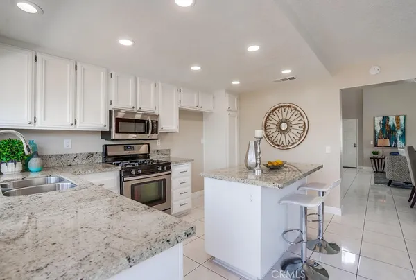 a kitchen with stainless steel appliances granite countertop a refrigerator a stove top oven a sink a dining table and chairs