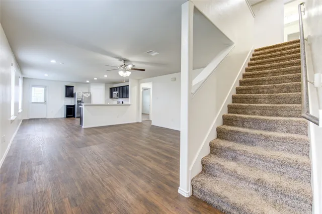 a view of an empty room with wooden floor and a ceiling fan