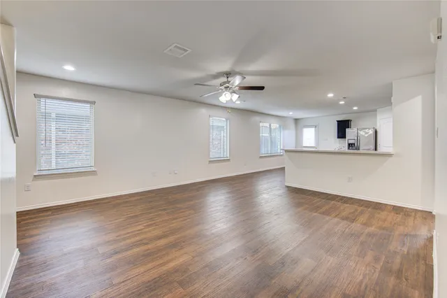 a view of an empty room with kitchen and a window