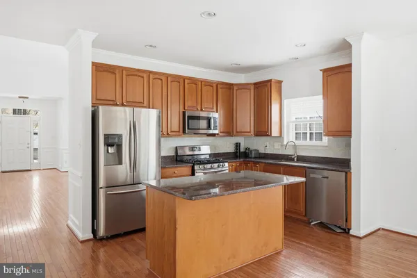 a kitchen with wooden cabinets a refrigerator stove a sink and dishwasher with wooden floor