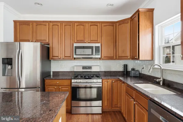 a kitchen with granite countertop a refrigerator stove and microwave