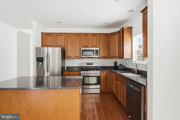 a kitchen with stainless steel appliances granite countertop a refrigerator a stove top oven a sink and dishwasher