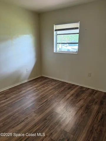 an empty room with wooden floor and a window