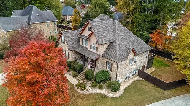 an aerial view of a house with a yard and a large tree