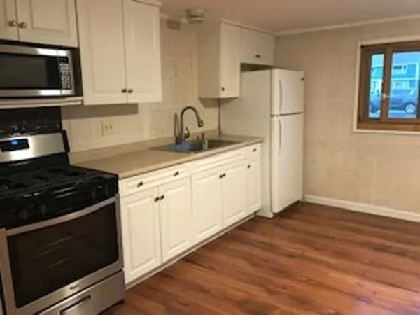 a kitchen with granite countertop a refrigerator stove and white cabinets