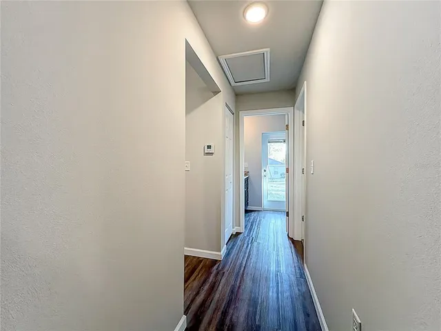 a view of a hallway view with wooden floor and a living room