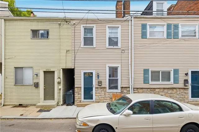 a view of a house with a car parked beside a road