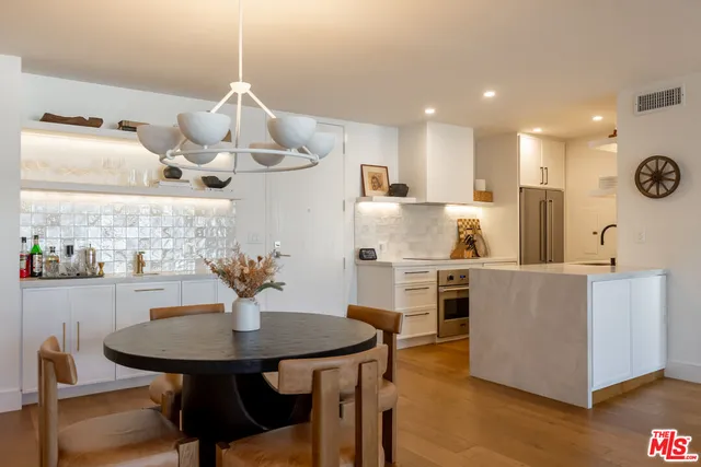 a kitchen with stainless steel appliances kitchen island granite countertop a table chairs and a refrigerator