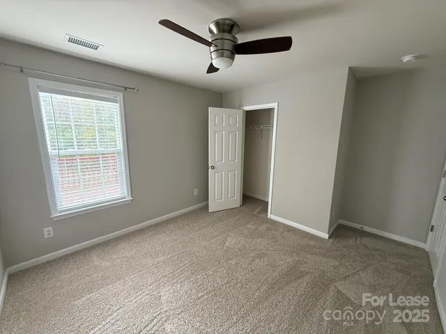 an empty room with windows and ceiling fan