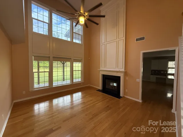 a view of a livingroom with wooden floor a fireplace and windows