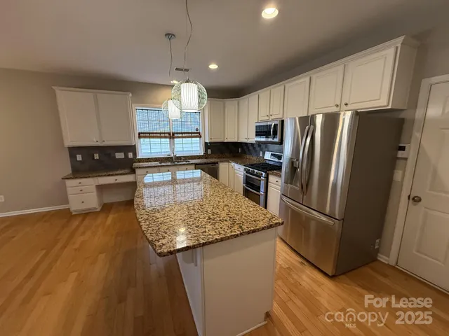 a kitchen with stainless steel appliances granite countertop a refrigerator a sink a stove a microwave and island