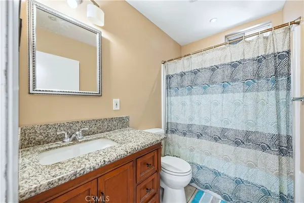a bathroom with a granite countertop sink a toilet and shower