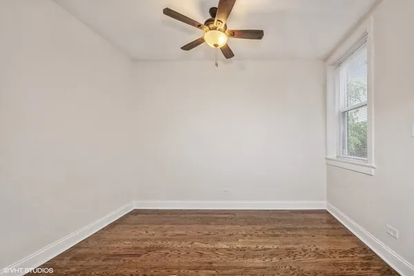 a view of an empty room with window and chandelier fan