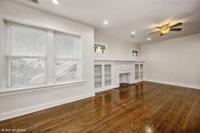a view of an empty room with a window and wooden floor