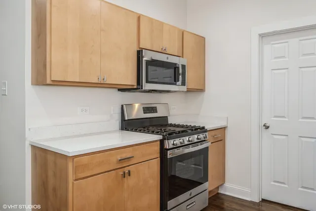 a kitchen with stainless steel appliances granite countertop white cabinets and a stove top oven