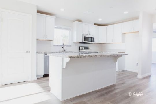 1340 Porter Street Ridgecrest, CA 93555 - Photo 8 of 20 a kitchen with stainless steel appliances a sink a stove a microwave a refrigerator a white cabinets and wooden floor