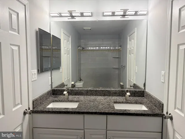 a bathroom with a granite countertop sink and a mirror