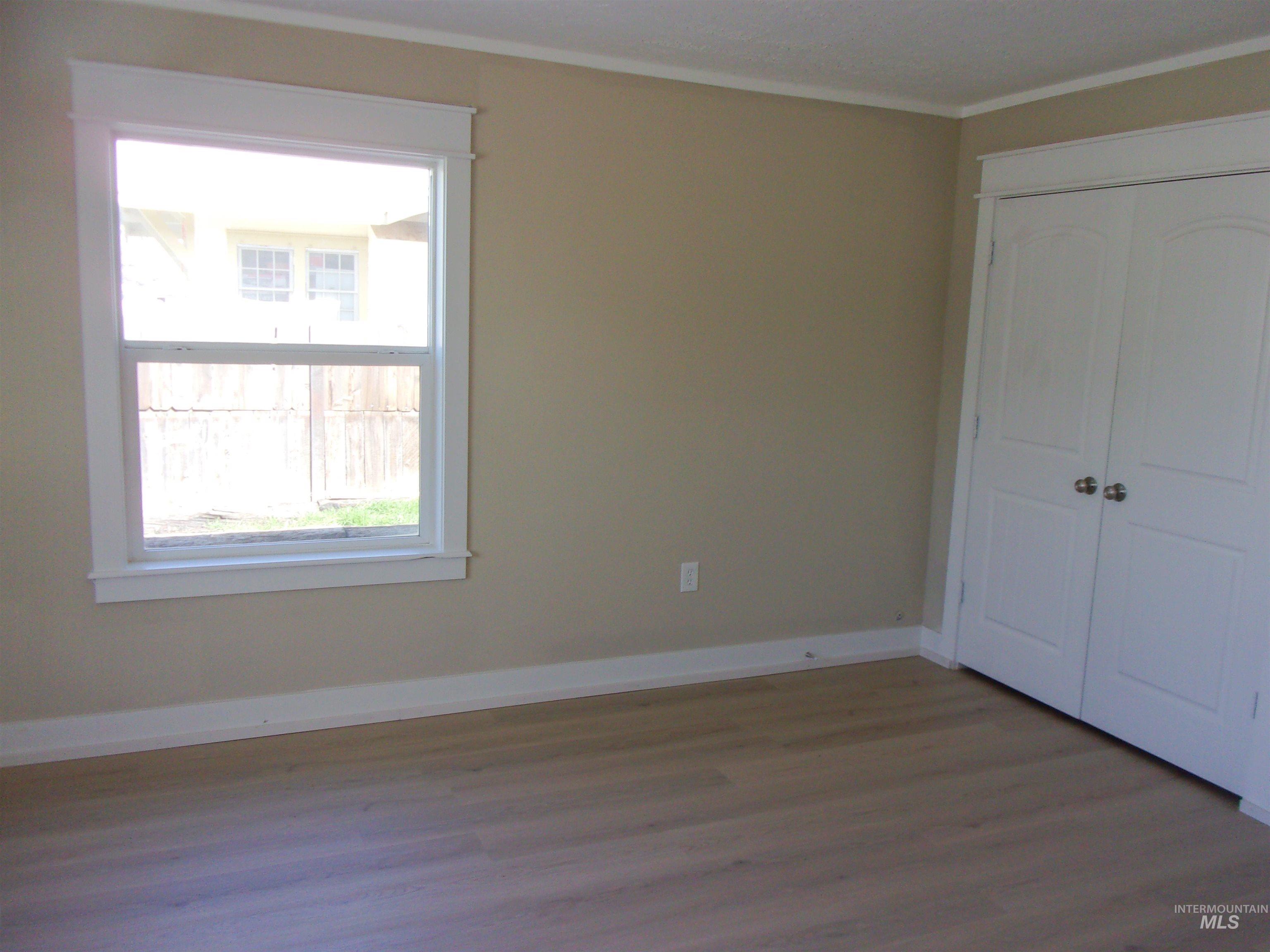 605 North 6th Street Parma, ID 83660 - Photo 13 of 46 Unfurnished bedroom with dark wood-style floors, a closet, and crown molding