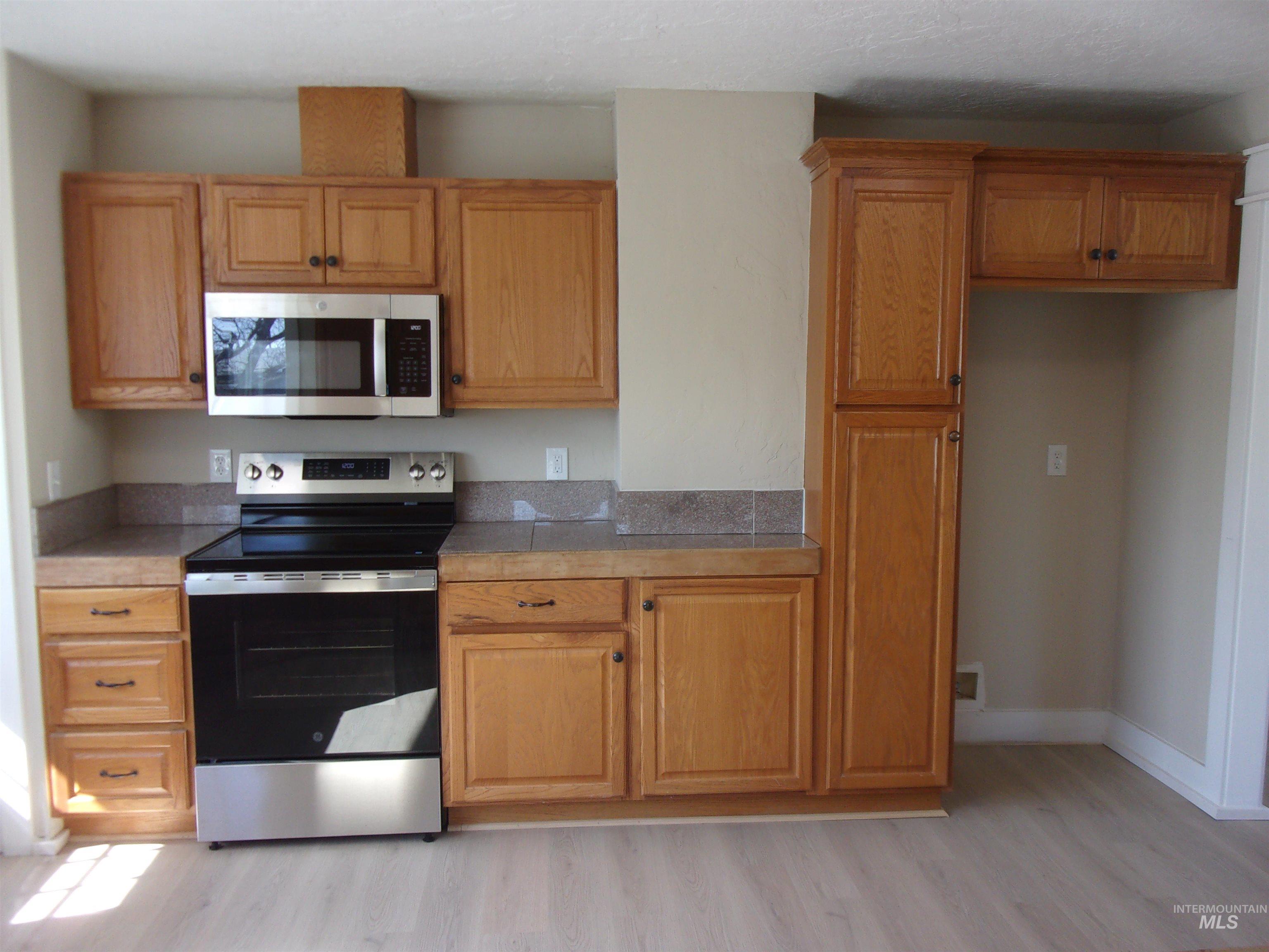 605 North 6th Street Parma, ID 83660 - Photo 32 of 46 Kitchen with stainless steel appliances, light wood-style flooring, wood finish cabinets, and tile counters