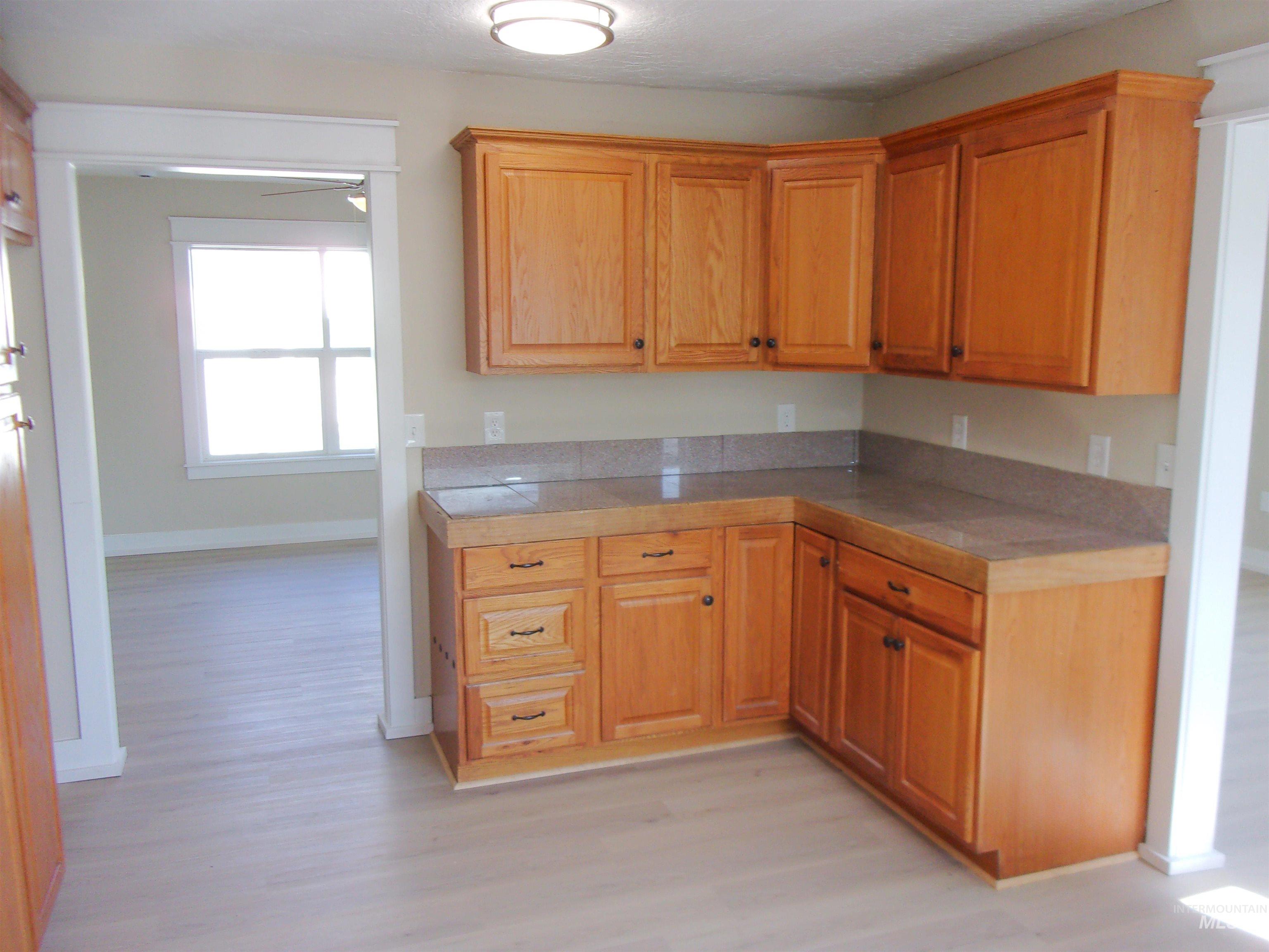 605 North 6th Street Parma, ID 83660 - Photo 33 of 46 Kitchen with tile counters, light wood finished floors, and wood finish cabinetry