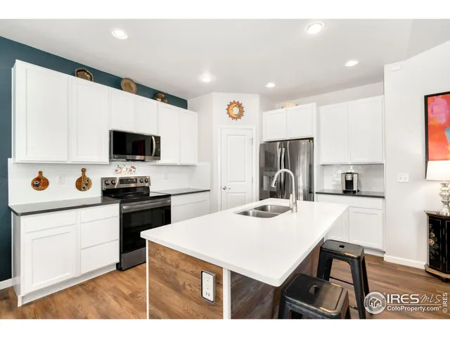 a kitchen with a stove a sink dishwasher and white cabinets with wooden floor