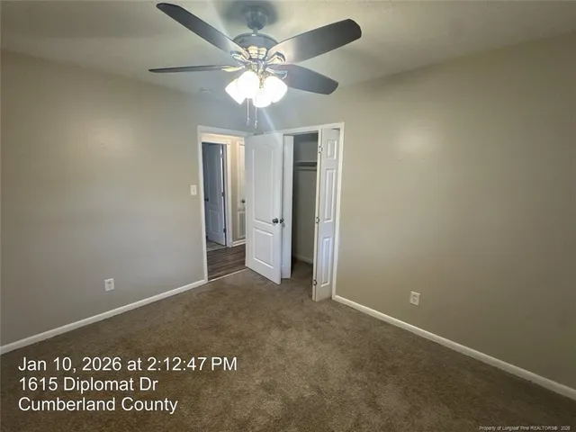 an empty room with a ceiling fan and carpet