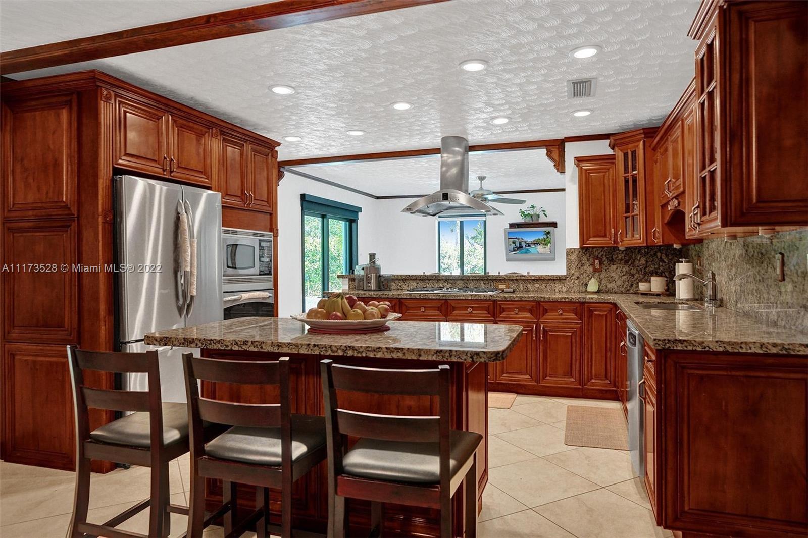 10801 Griffing Boulevard Biscayne Park, FL 33161 - Photo 64 of 77 a kitchen with stainless steel appliances granite countertop wooden cabinets a sink and a stove