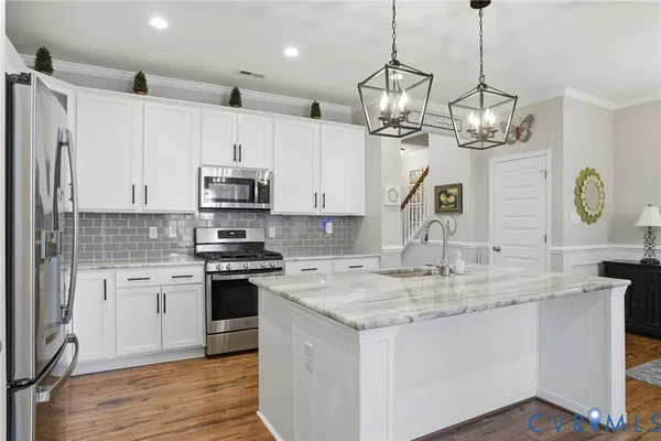 a kitchen with kitchen island granite countertop a sink a counter space appliances and cabinets