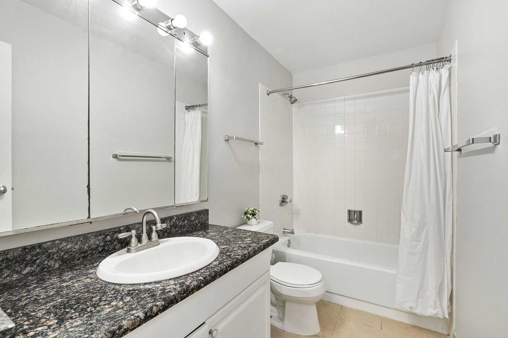 5320 North Sheridan Road, Unit 403 Chicago, IL 60640 - Photo 21 of 36 a bathroom with a granite countertop sink toilet a mirror a bathtub and shower