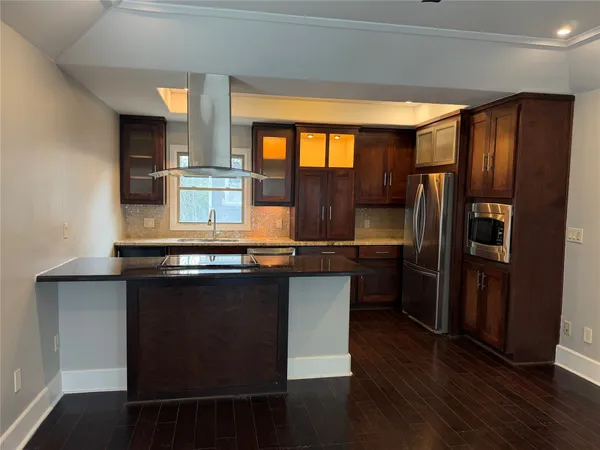 a kitchen with granite countertop a refrigerator and wooden cabinets