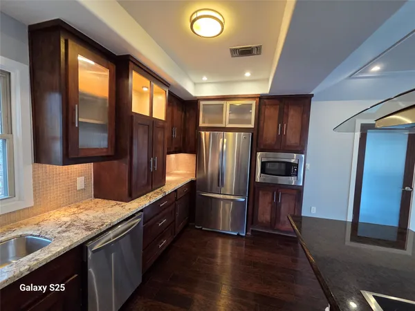 a kitchen with stainless steel appliances granite countertop a refrigerator a sink and wooden cabinets