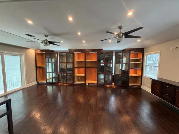 an empty room with wooden floor and a ceiling fan