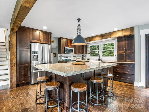 a kitchen with stainless steel appliances granite countertop a table chairs and a refrigerator
