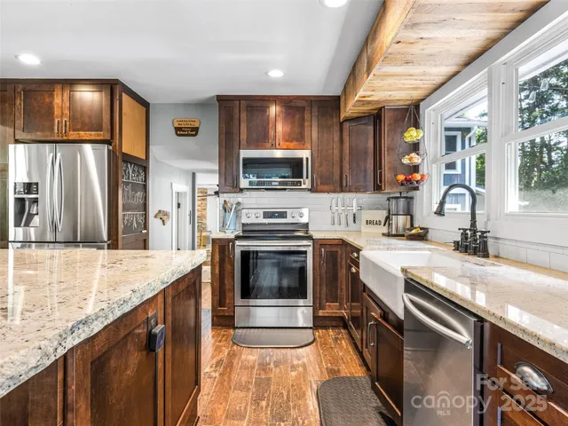 a kitchen with stainless steel appliances granite countertop a stove a sink and a microwave