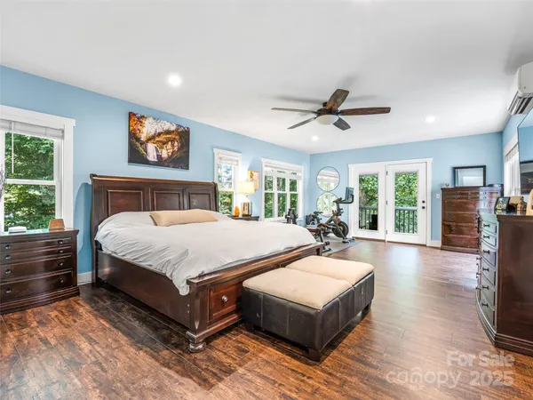 a spacious bedroom with a large bed a chandelier and windows