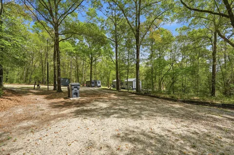 a view of a house with a yard and large trees