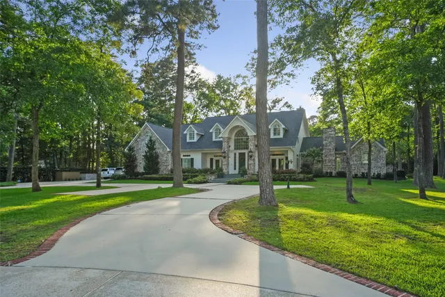 a front view of a house with garden and trees
