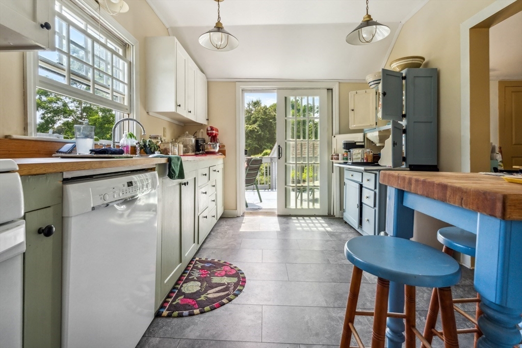 1251 County Road Bourne, MA 02534 - Photo 8 of 42 a kitchen with stainless steel appliances kitchen island granite countertop a table chairs in it and wooden floors